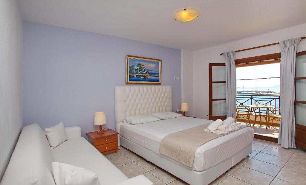 a white bedroom with a bed and a balcony at Anna Maria - Vanessa Apartments in Neo Klima