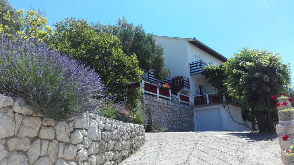 a house with a stone wall and purple flowers at Apartments Bojana Rab in Rab