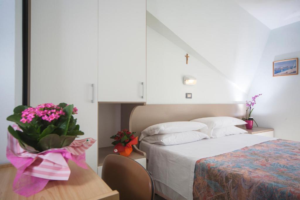 リミニにあるHotel Latiniのベッドルーム1室(ベッド1台、花のテーブル付)