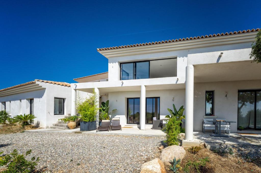 een wit huis met glazen ramen en een oprit bij Villa Les Restanques in Bandol