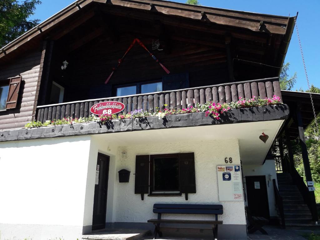 a building with a balcony with flowers on it at Fichtenblockhütte in Sonnenalpe Nassfeld