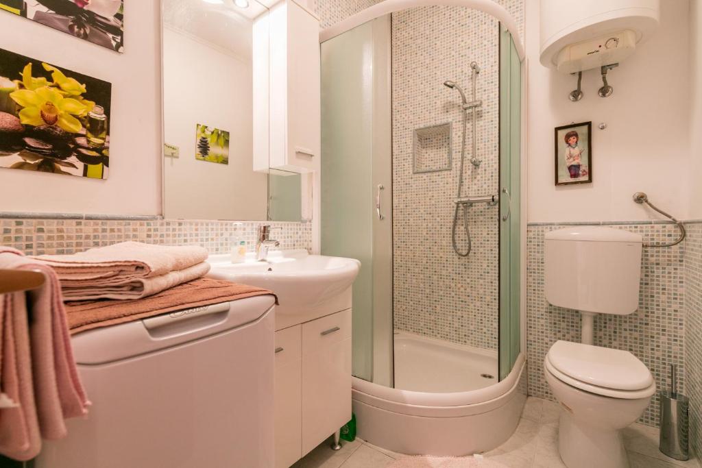 y baño con ducha, aseo y lavamanos. en Apartments Kastelani, en Komiža
