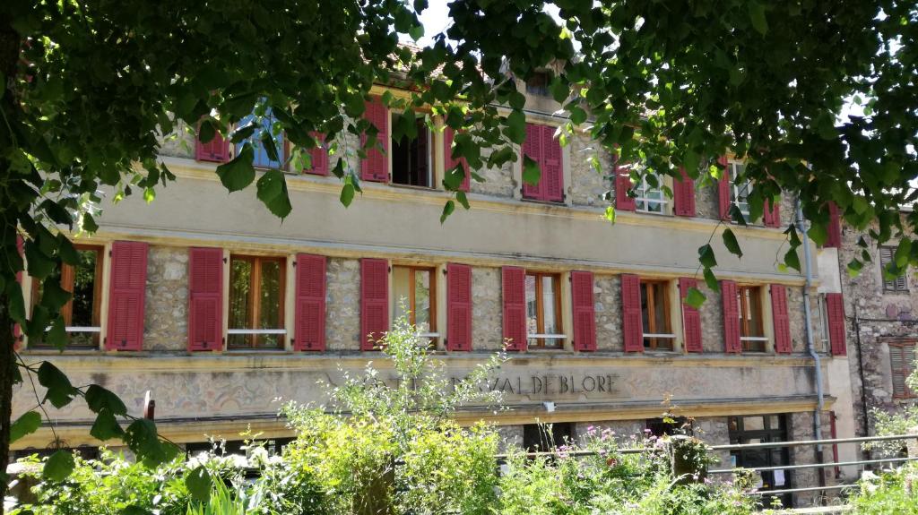 Un vieux bâtiment avec des volets rouges dans l'établissement Hôtel de Valdeblore, à Valdeblore