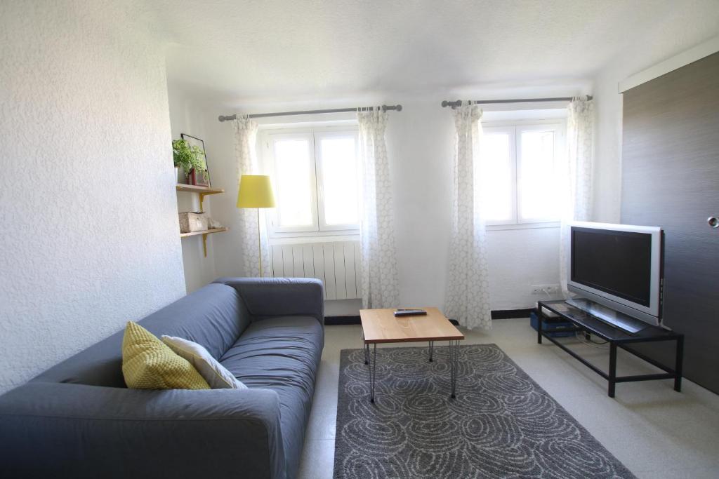 a living room with a blue couch and a television at Au dessus des platanes in Carpentras