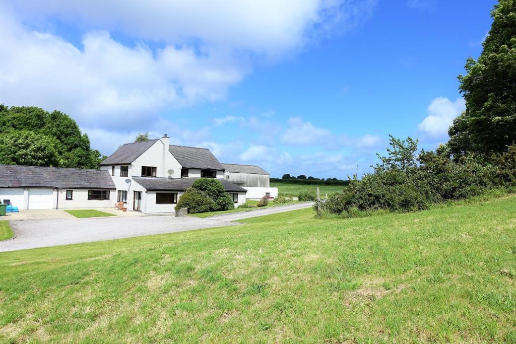 a white house with a grassy field in front of it at Tyddyn Crwn Country-House Apartments in Beaumaris