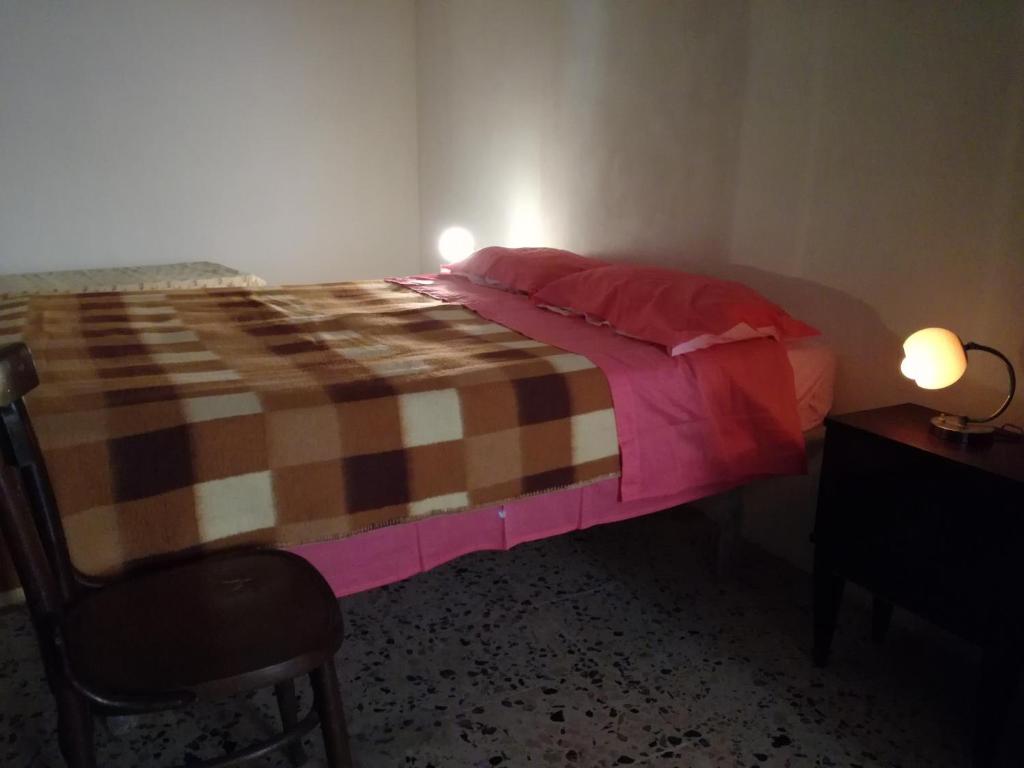 MistrettaにあるCasa Mariuccia - economico e il più centraleのベッドルーム1室(ピンクの毛布と椅子付きのベッド1台付)