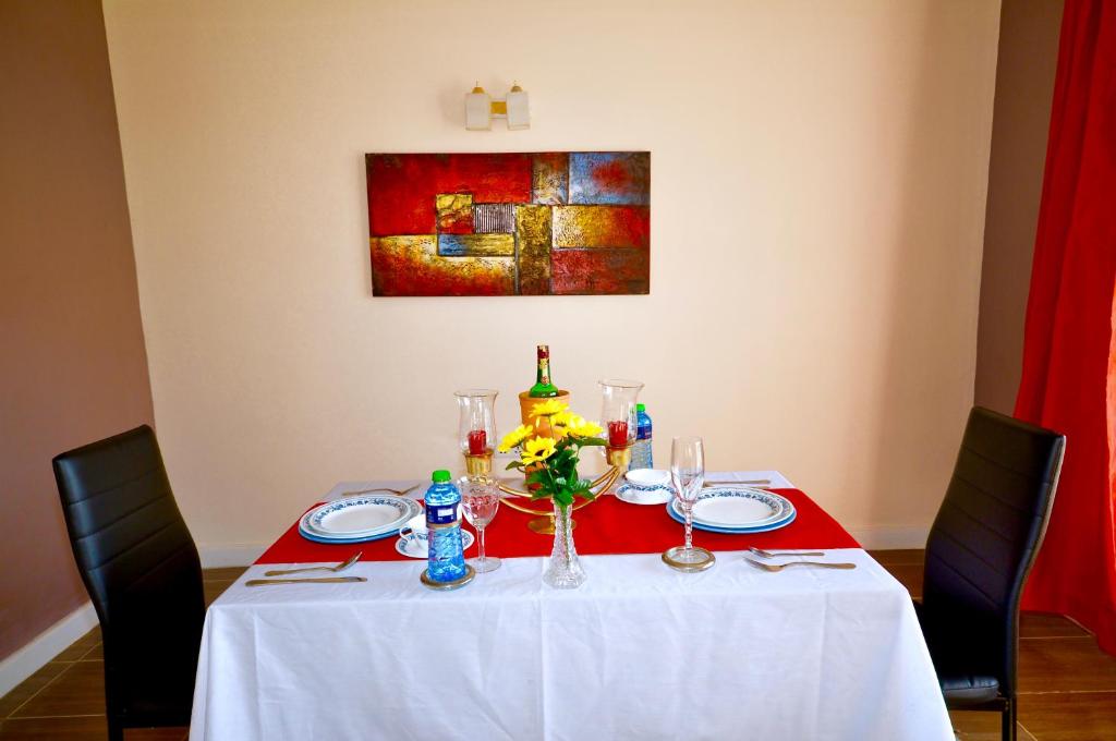 a table with a white table cloth and a bottle of wine at Lamanis Haven in Kakamega