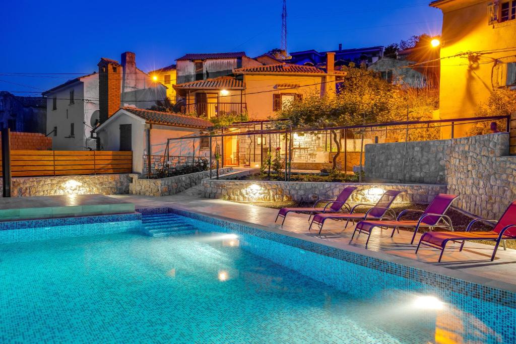 a swimming pool with chairs next to a building at House Obrš in Mošćenička Draga