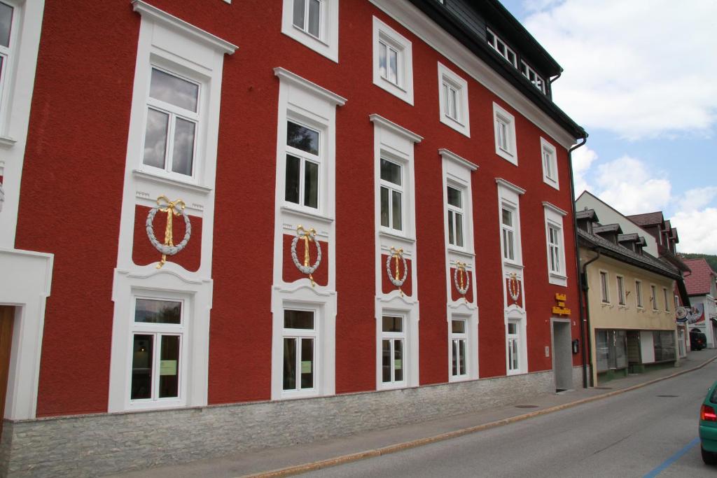 a red building with white windows on a street at Hotel zum Heiligen Geist in Mariazell