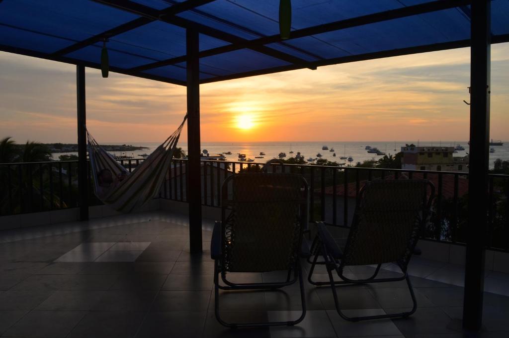 einen Balkon mit 2 Stühlen und einer Hängematte bei Sonnenuntergang in der Unterkunft Dolphin House in Puerto Baquerizo Moreno