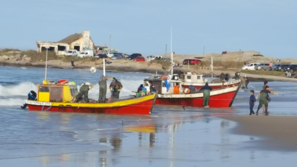 dos barcos en la playa con gente en ella en Maxival Cabañas, en Punta del Diablo