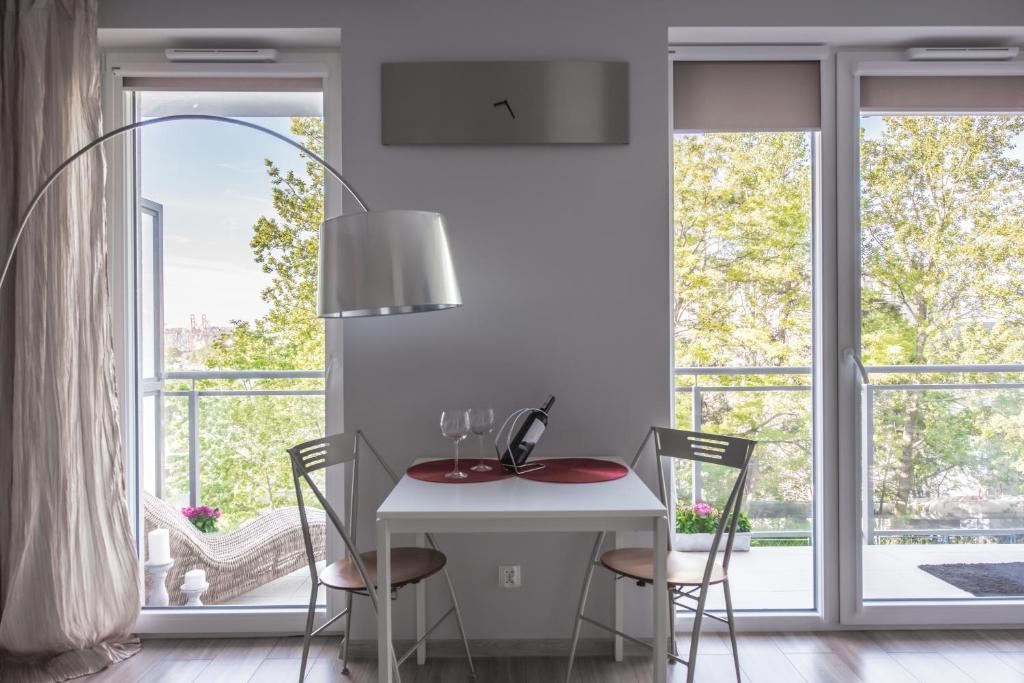comedor con mesa blanca, sillas y ventanas en Kapitańska Apartament en Gdynia