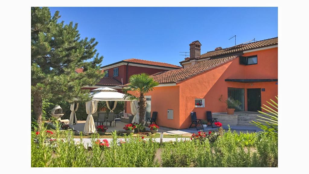 a house with a patio and a garden with flowers at Apartments Gvarda in Umag