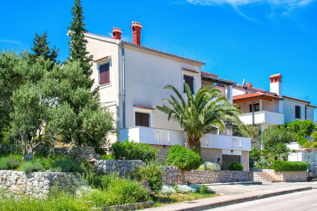 a white house with palm trees in front of a street at Apartmani GORDANA in Mali Lošinj