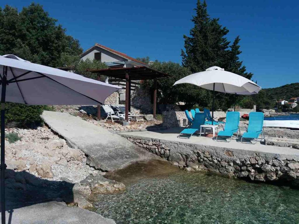 a group of chairs and umbrellas next to a pool at Villa Rose Ann in Rogoznica