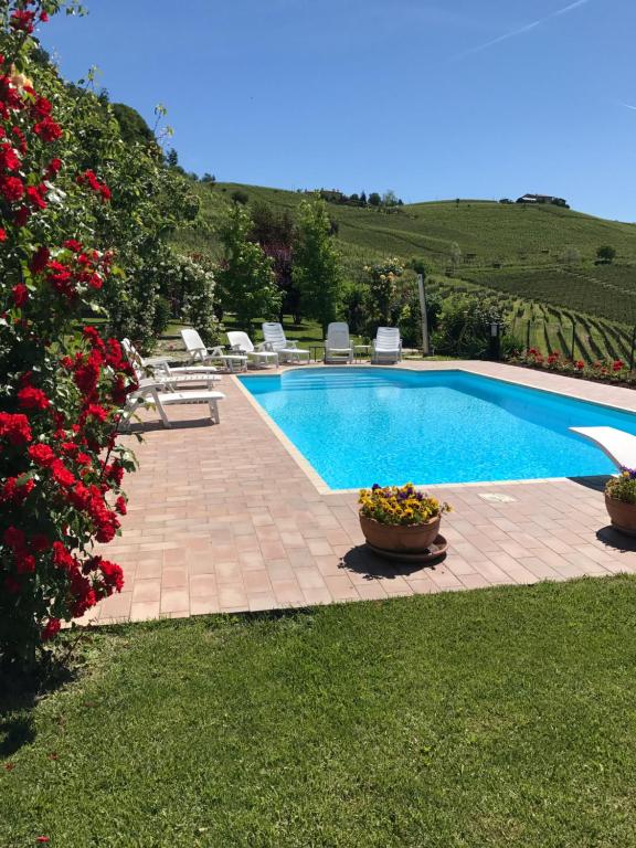a swimming pool with chairs and flowers in a yard at Residence delle Rose in Barolo