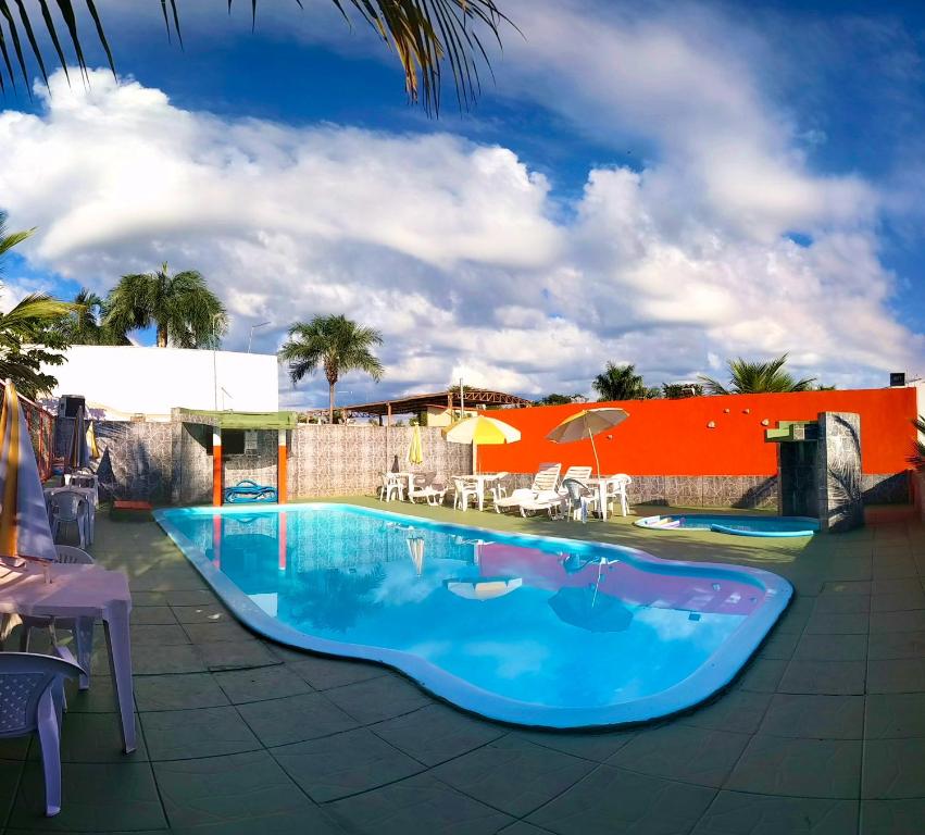 a large blue swimming pool with chairs and umbrellas at Pousada Sol Nascente in Olímpia