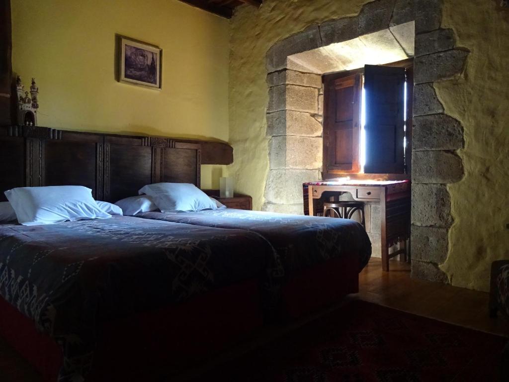 1 dormitorio con cama y pared de piedra en La Casona de Villanueva de Colombres, en Villanueva