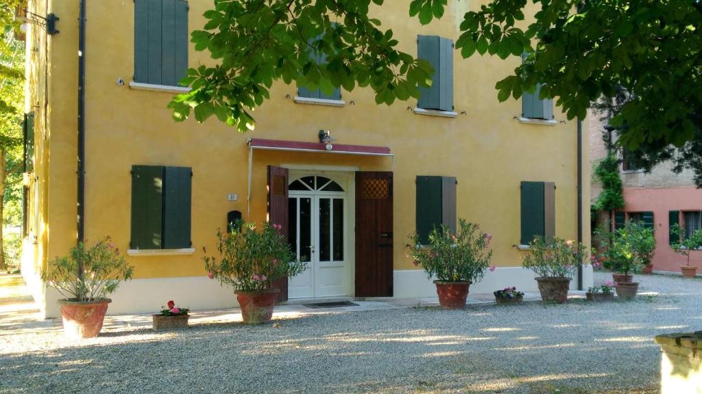 un edificio amarillo con persianas verdes y una puerta blanca en B&B IL NAVIGLIO, en Bastiglia