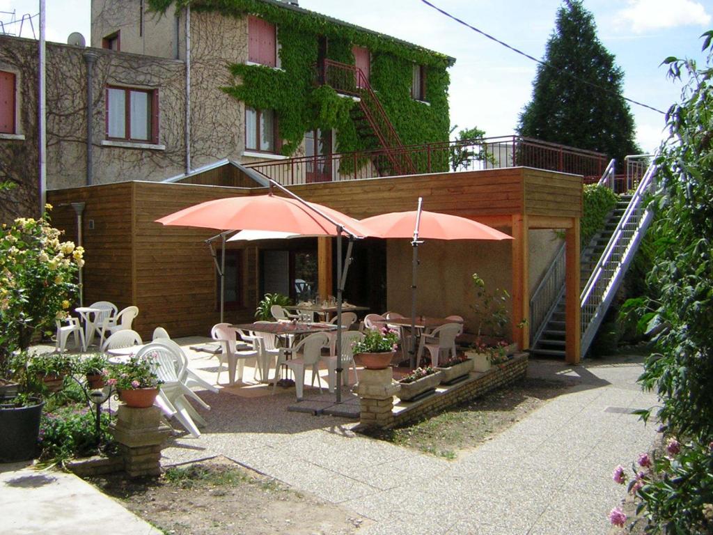 a patio with tables and umbrellas in front of a building at Hôtel Bertrand in Bar-le-Duc