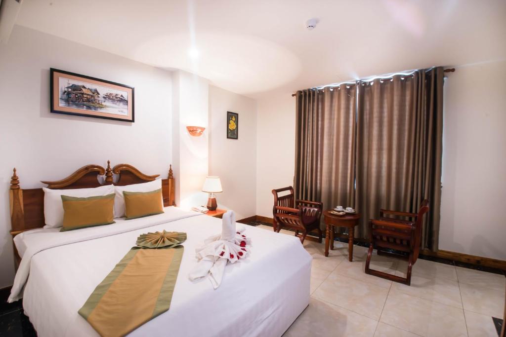 a bedroom with a bed, chair, table and a lamp at Relax Hotel in Phnom Penh