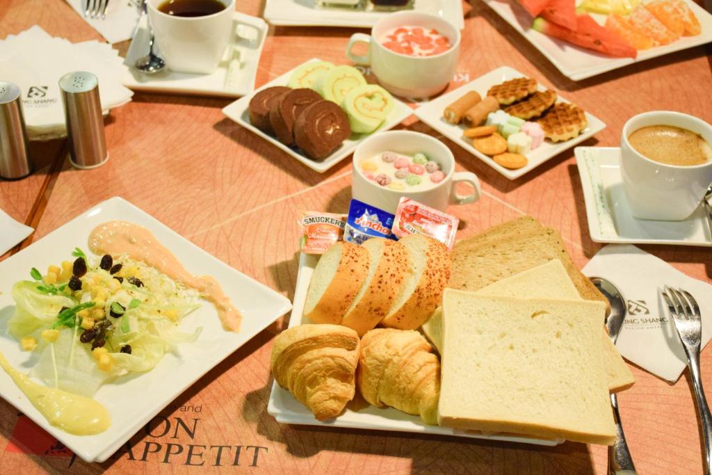 a table with plates of bread and pastries and cups of coffee at Kung Shang Design Hotel in Kaohsiung