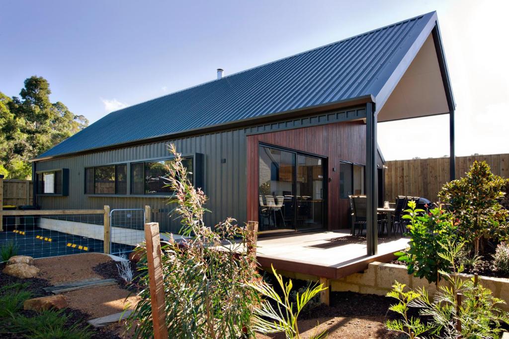 una pequeña casa con techo negro en Margaret River Bungalow-1-street - pet friendly, en Margaret River Town