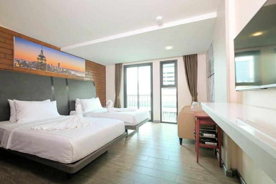 um quarto de hotel com duas camas e uma secretária em BBHouse Khlongtan em Bangkok