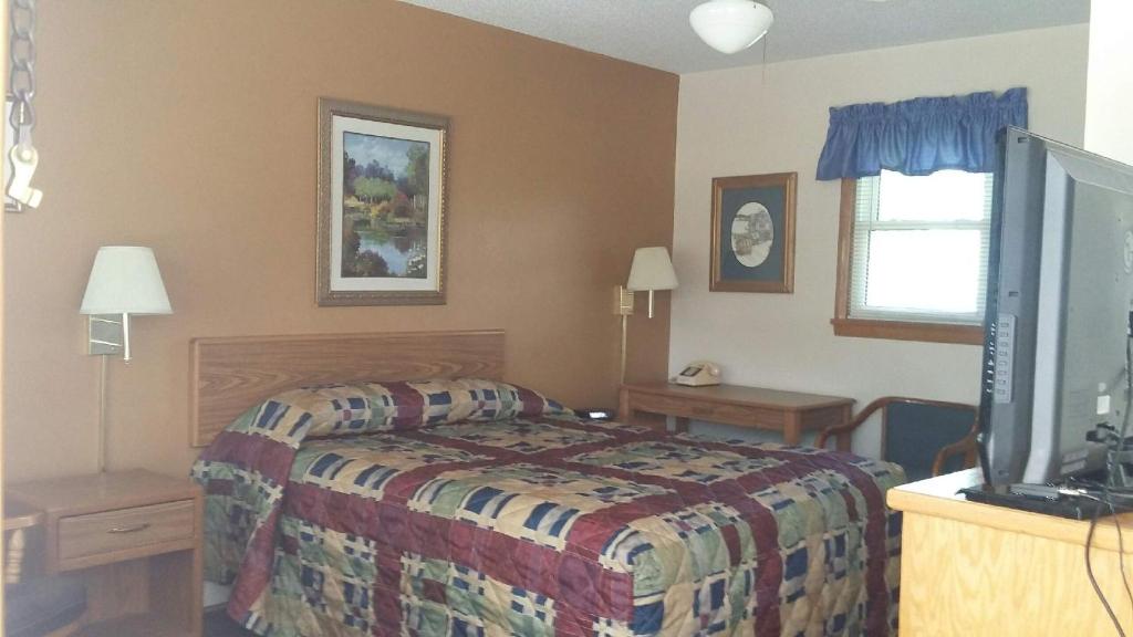 a bedroom with a bed and a flat screen tv at Skyline Motel in Alexandria