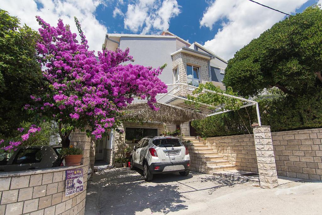 een auto geparkeerd voor een huis met paarse bloemen bij Villa Mađor in Makarska