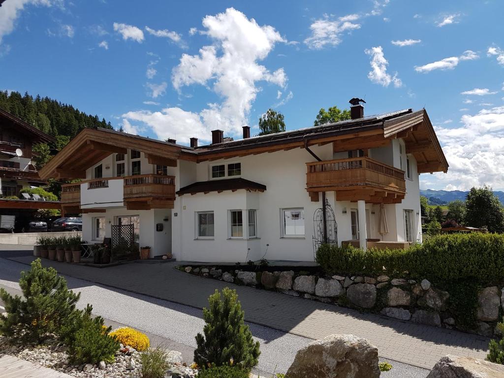 ein weißes Haus mit Holzbalkonen darauf in der Unterkunft Appartement Angelika in Brixen im Thale
