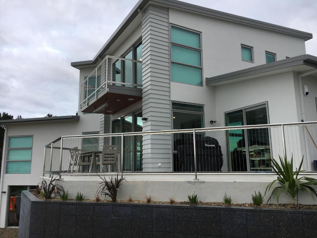 a white house with a balcony with chairs at Captains View in Kaiteriteri