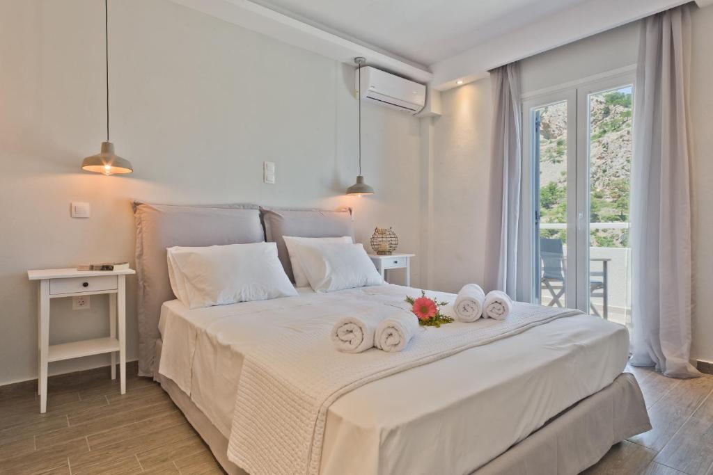 a bedroom with a large white bed with towels on it at Antikri villas in Kyra Panagia