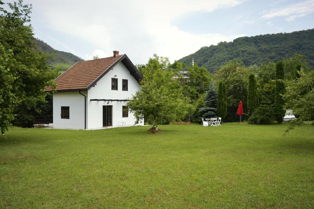 a white house in a field of green grass at Apartment Holiday - River view beside Pyramid in Visoko