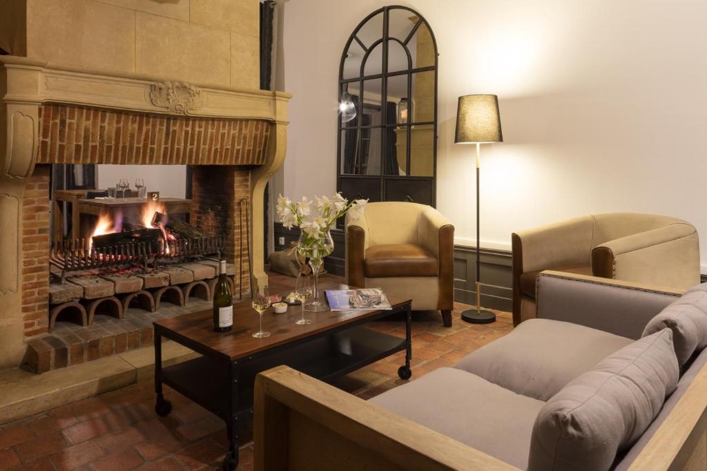 a living room with a fireplace and a couch and chairs at Contact Hôtels Le Savigny & Spa in Blacé