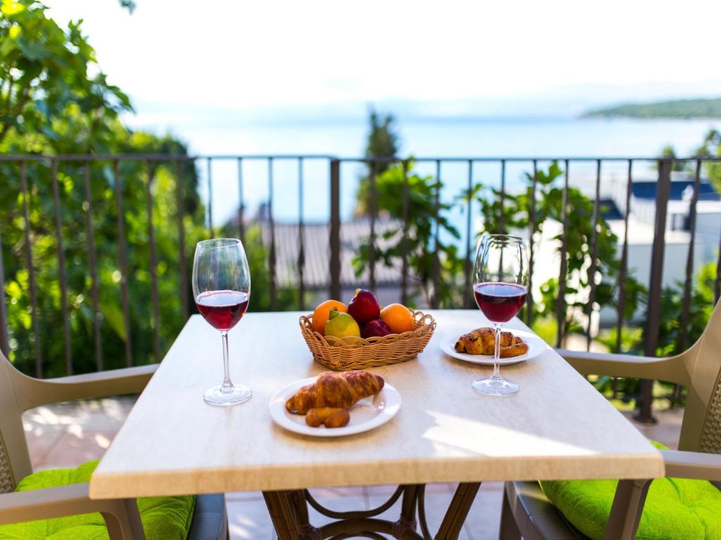 a table with two glasses of wine and a basket of fruit at Apartment in Njivice/Insel Krk 27659 in Njivice