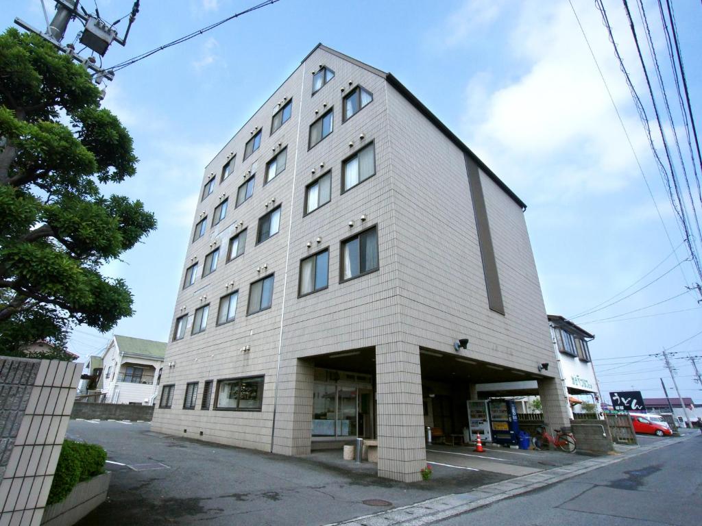 a tall white building on the side of a street at Hotel Trend Saijo in Saijo
