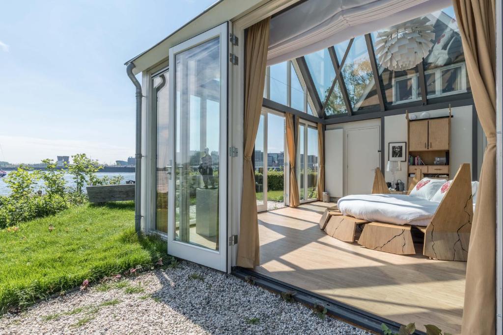 een slaapkamer in een glazen huis met een bed bij The Panorama Suite (Mandelahuisje) in Amsterdam