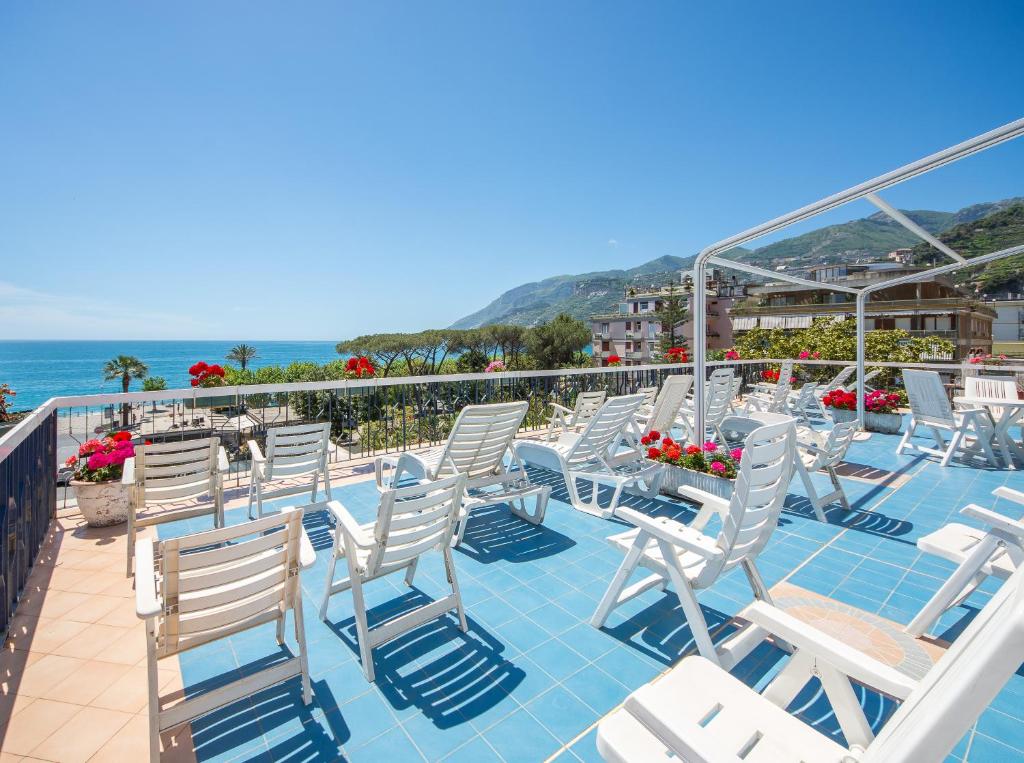 a row of white chairs on a balcony with the ocean at La Residenza Aparthotel in Maiori