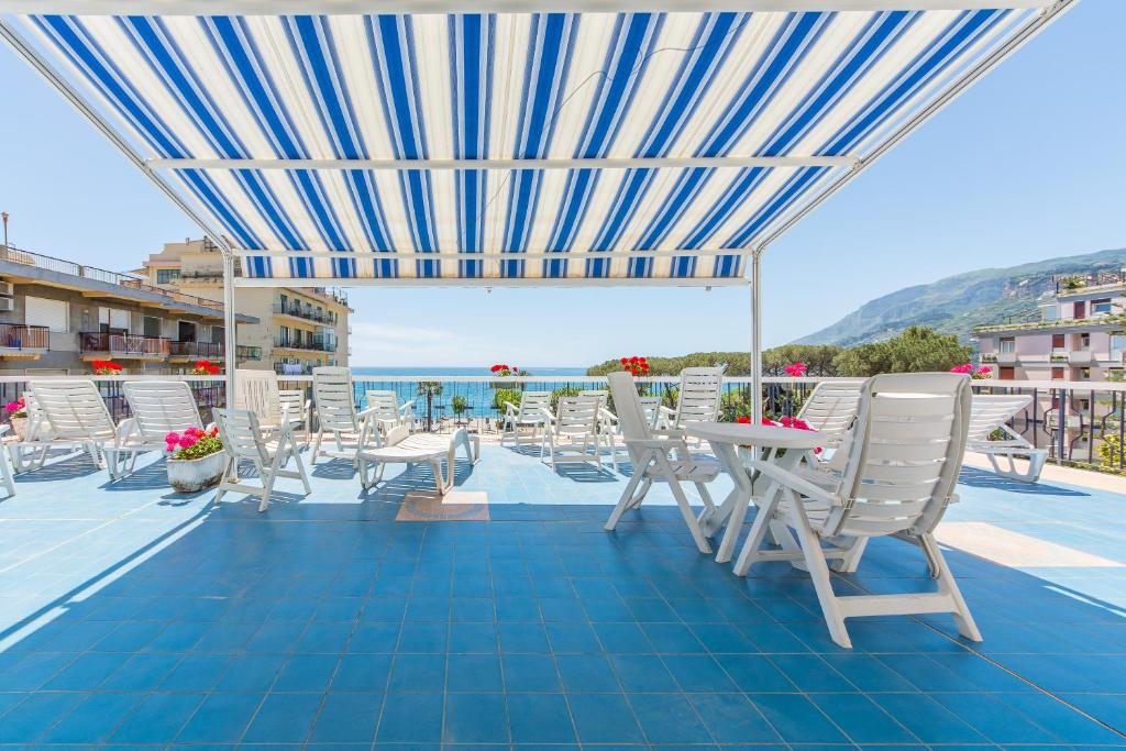 a patio with white chairs and a table and an umbrella at La Residenza Aparthotel in Maiori