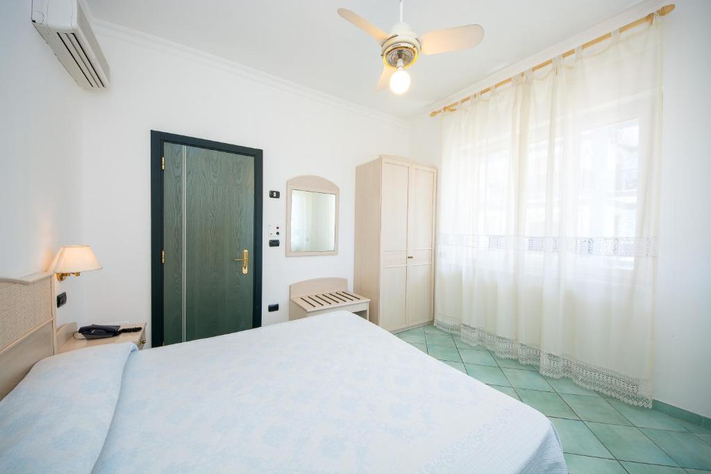 a bedroom with a white bed and a green door at La Residenza Aparthotel in Maiori