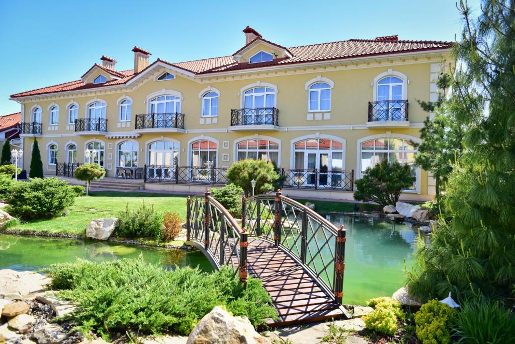 een groot geel gebouw met een brug over een rivier bij Hotel Villa Venice in Vinnytsya