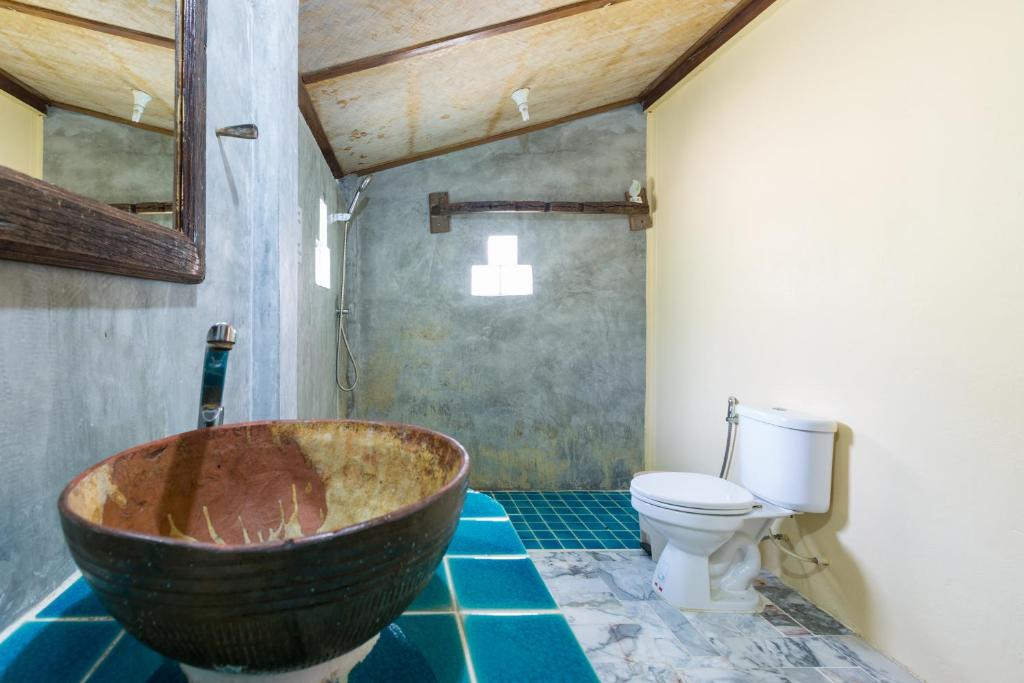a bathroom with a large wooden bath tub next to a toilet at Bottle Beach 1 Resort in Bottle Beach