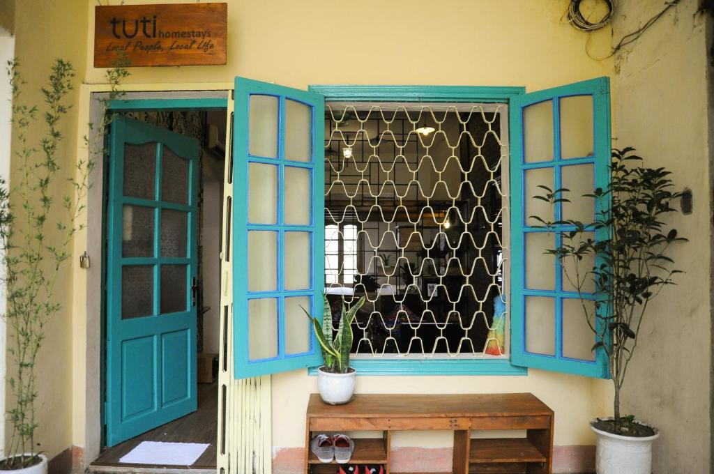 okno z niebieskimi drzwiami i drewnianą ławką w obiekcie Tuti Tong Dan Homestay w mieście Hanoi