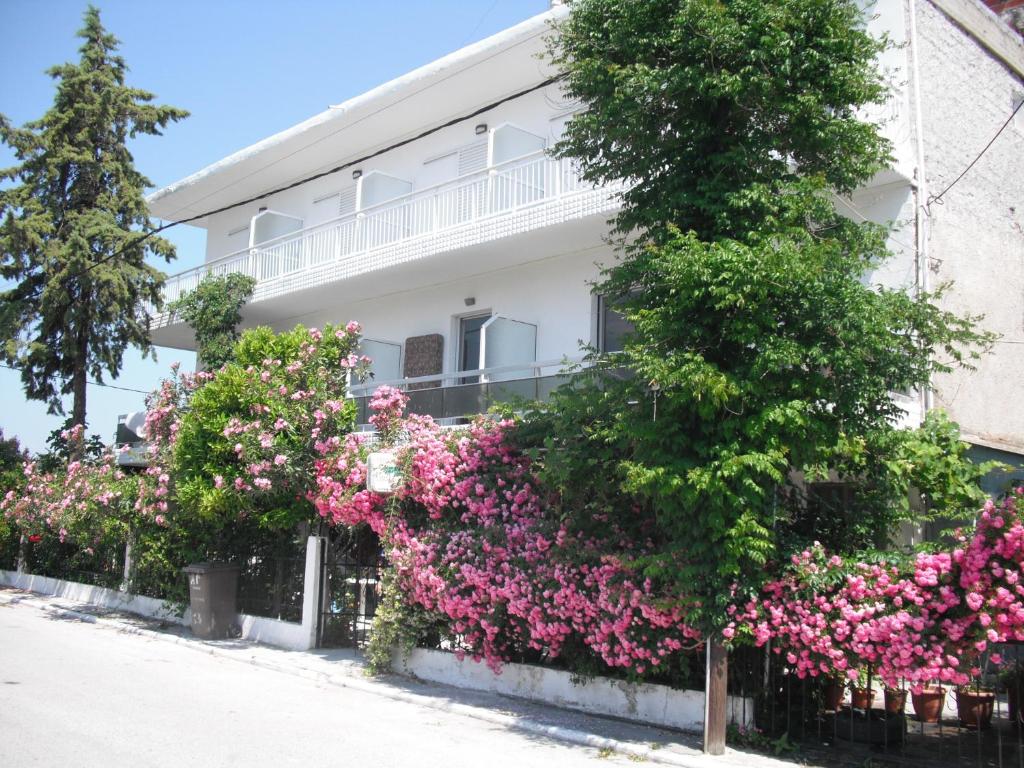 a white building with pink flowers in front of it at Aris House in Paralia Katerinis