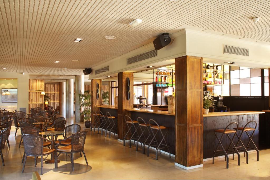 un restaurante con un bar con mesas y sillas en Luna Park Hotel Yoga & Spa, en Malgrat de Mar