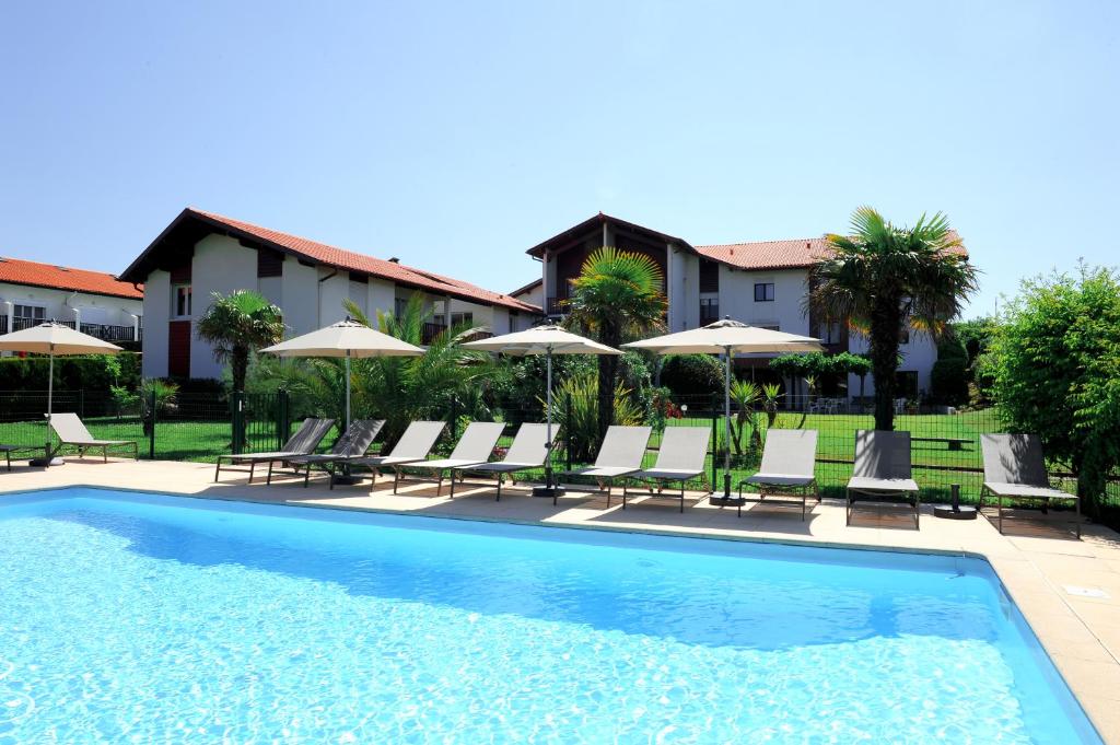 a swimming pool with lounge chairs and umbrellas at Hotel & Appartements Gochoki in Bidart