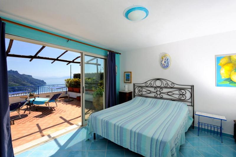 a bedroom with a bed and a balcony with a view at BB Ravello Houses in Ravello