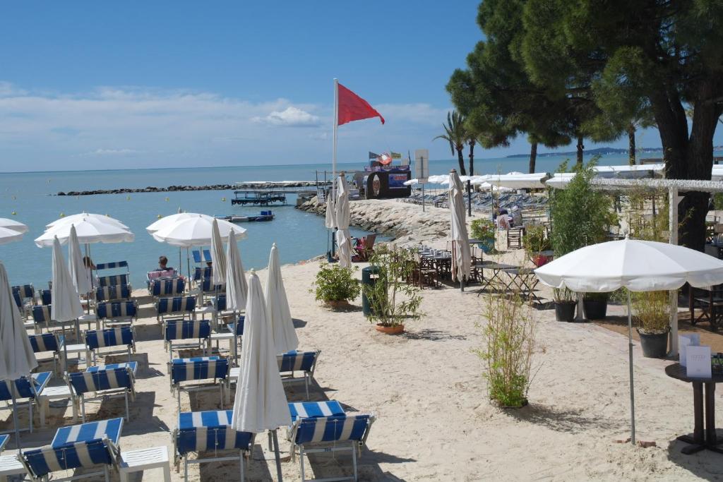 - un groupe de chaises longues et de parasols sur une plage dans l'établissement Villa Soraya , quiet location with big garden near beach and old town of NICE, à Nice