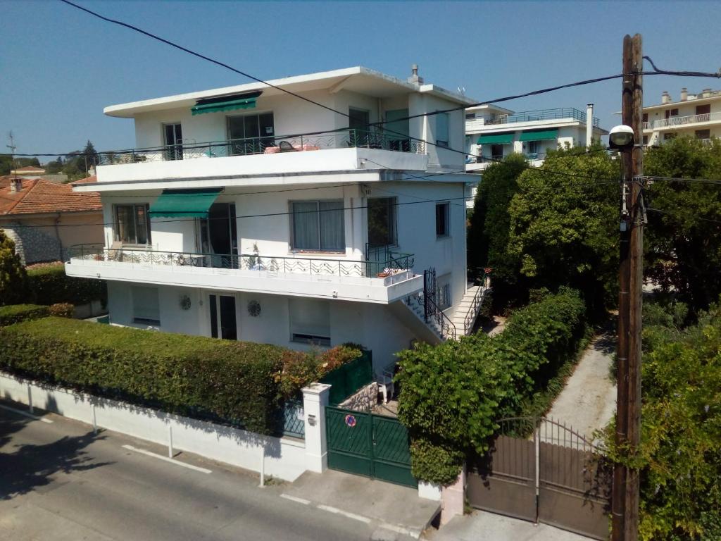 une maison blanche avec une clôture verte et des buissons dans l'établissement Résidence Stella Maris, à Antibes